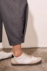 Pantalón gris a rayas verticales blancas, de corte recto y tiro medio.