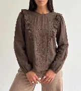 Blusa de manga larga color marrón, con escote redondo, detalle de volados en los hombros y bordado floral en el frente.