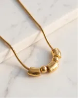 Collar de acero dorado con cadena tipo serpiente y dije central compuesto por tres piezas cilíndricas intercaladas con dos esferas pequeñas.