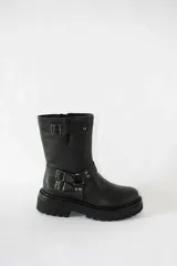 Bota de caña media confeccionada en cuero negro, con suela gruesa track antideslizante. Presenta un diseño estilo biker con estribo integrado, hebillas metálicas decorativas y una correa ajustable en la parte superior de la caña. Incluye cierre lateral para facilitar el calce.