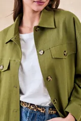 Sobrecamisa verde militar de lino y viscosa, corte oversize, con cuello camisero, cierre frontal con botones, mangas largas con puños abotonados, dos bolsillos de parche con solapa en el pecho y ruedo recto.