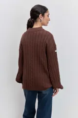Sweater de tejido de punto color bordó, con cuello alto, mangas largas con puños ajustados y diseño de trenzas verticales.