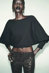 Jersey corto de punto color negro, con cuello barco y mangas largas abullonadas, terminadas en puño.