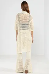 Camisa larga de punto abierto color crema, con cuello clásico, manga corta y cierre frontal con botones.