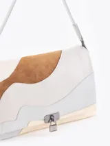 Cartera de hombro con diseño de ondas en combinación de cuero vacuno y descarne en tonos neutros. Presenta una estructura semirrígida, cierre frontal con aplique metálico tipo candado y correa de hombro ajustable.
