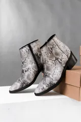 Botas cortas de cuero vacuno con estampado de piel de serpiente en tonos grises y blancos, con cierre lateral YKK, taco de madera foliado en cuero de 5 cm y caña de 12 cm.