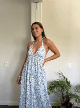 Vestido largo blanco con estampado floral celeste, escote halter y espalda descubierta.