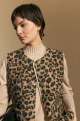 Chaleco de textura afelpada con estampado animal print, cuello redondo y cierre frontal con botones a presión. Cuenta con bolsillos laterales y ribetes al tono.