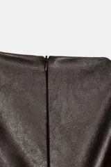 Vestido corto de efecto piel con cuello barco y diseño sin mangas. Presenta un bajo abullonado con elástico interior y cierre de cremallera en la espalda.