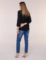 Blusa celeste de silueta suelta y textura liviana, con escote en V, cuello mao y cierre frontal de botones. Cuenta con alforzas verticales en el pecho y mangas tres cuartos con puños elastizados y detalle de galón calado.