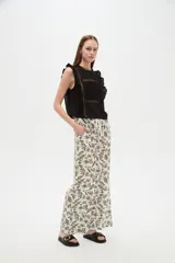 Pantalón de algodón estampado con diseño botánico de hojas en tonos verdes sobre base blanca, de corte holgado, tiro medio y cintura elástica con cordón de ajuste ajustable.