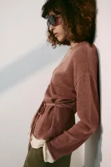 Chaqueta de punto color marrón con detalles en tono marfil en el escote en V, los puños y el ruedo. Cuenta con manga larga, cierre frontal con botones y un cinturón fino ajustable del mismo tejido.