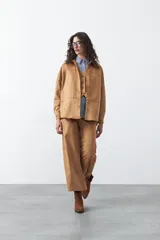 Sobrecamisa de gamuza color marrón, de silueta relajada, con cuello camisero, botones frontales y bolsillos de parche en el pecho.