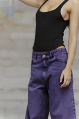 Jean de corte oversized y tiro medio-alto, confeccionado en denim de color violeta con diseño de cinco bolsillos y cierre frontal con botón y cremallera.