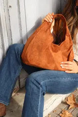 Cartera tipo hobo de gamuza negra, con diseño minimalista y asa integrada.