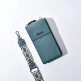 Porta celular turquesa con diseño tejido en la parte inferior, solapa con cierre magnético y correa de tela estampada desmontable.