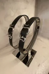 Cinturón de cuero negro con hebilla plateada en forma de serpiente.