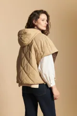 Chaleco de nylon matelaseado color beige, con diseño acolchado de rombos, cierre frontal y corte amplio tipo capa.