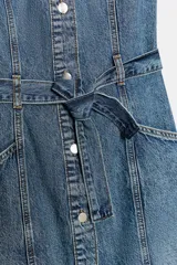 Vestido corto de denim con cuello solapa, manga corta y cierre frontal con botones metálicos. Presenta bolsillos delanteros y un cinturón del mismo tejido para ajustar a la cintura.