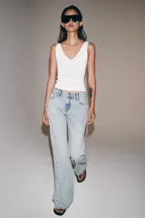 Jeans de tiro bajo con diseño de pierna acampanada y corte relajado. Presentan cinco bolsillos, trabillas en la cintura y cierre frontal con cremallera y botón. Confeccionados en denim con efecto lavado.