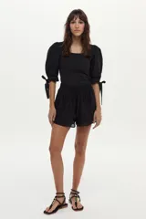 Top negro combinado con cuerpo de canalé y mangas abullonadas de popelina con lazos ajustables en los puños, y escote redondo.
