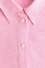 Camisa de corte oversized en tejido liviano de lino y viscosa, de color rosado. Cuenta con cuello clásico, cierre frontal de botones, hombros caídos y mangas largas con puños abotonados. El diseño se completa con un bajo redondeado.