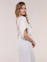 Vestido largo blanco confeccionado en viscosa con hilos de lurex, escote en V profundo con lazo y borlas, mangas kimono y falda fluida con volados en el ruedo.