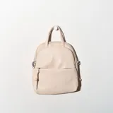 Mochila pequeña color beige con doble compartimento con cierre y asa corta superior.
