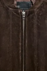 Cazadora tipo bomber de Zara confeccionada en piel de ante 100%. Presenta cuello redondo, cierre frontal con cremallera metálica, bolsillos delanteros con solapa y bajo con acabado elástico.