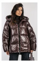 Campera oversize color marrón brillante con capucha, cierre frontal de doble cursor y bolsillos laterales con cremallera. Tiene relleno natural y ajuste inferior con cordón.