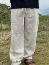 Pantalón de lino beige y crudo a rayas, de corte ancho y relajado.