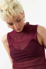 Top negro sin mangas de cuello alto, confeccionado en tela semitransparente con textura acanalada y acabado brillante.