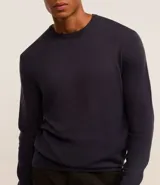 Suéter de punto color borgoña, con cuello redondo, sisas ligeramente desplazadas y bajo y puños acanalados.