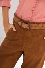 Pantalón de gamuza color marrón, de tiro medio y corte slouchy. Presenta bolsillos laterales y traseros, cierre metálico frontal y forro interno con stretch.