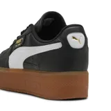 Championes Puma Palermo Elevata de cuero negro con franja lateral blanca, detalles dorados y suela marrón de plataforma.