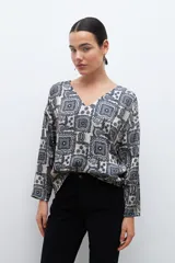 Blusa beige con estampado de arabescos en azul, con escote en V y mangas largas.