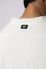 Camisa de manga larga confeccionada en tejido de lino con textura, de corte holgado y diseño versátil con cierre frontal de botones.