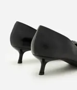 Zapato tipo scarpin de poliuretano color negro, con punta fina, escote en V y taco bajo tipo kitten heel.