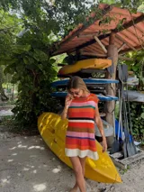 Vestido corto tejido en punto jersey con diseño de rayas horizontales multicolores. Presenta una silueta recta, cuello redondo y terminaciones hechas a mano en crochet.