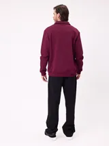 Buzo tipo polo de manga larga color bordó, con cuello camisero y cierre frontal de botones. Presenta estampado gráfico frontal con el número 85, el logo de la marca Rusty y un escudo deportivo.