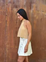 Falda corta tipo wrap de cuero color crudo, con diseño cruzado y ajuste mediante tiritas laterales.