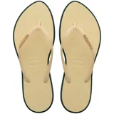 Ojotas Havaianas modelo Slim Point, con base color beige y borde oscuro. Presentan tiras finas en tono beige con el logo de la marca en relieve en color dorado.