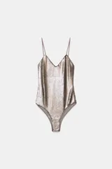 Body de escote en pico con tirantes finos, completamente cubierto de lentejuelas brillantes. Cuenta con cierre en el bajo mediante botones a presión.