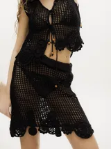 Falda corta de tejido calado y crochet color negro, con pretina elástica y detalles de apliques tejidos en el bajo.