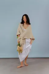 Ruana tejida a mano en lana merino color beige, con textura suave, detalles de brillos y flecos en los bordes.