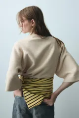 Jersey de punto verde militar, con cuello subido y mangas largas anchas de corte acampanado.