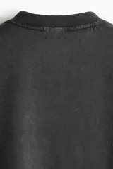 Remera deportiva de corte boxy y holgado con tecnología DryMove, en color gris oscuro con efecto gastado. Presenta hombros caídos, cuello redondo ribeteado y un gran estampado frontal en tonos claros con la palabra 'RUNNING' y siluetas de personas corriendo.