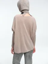 Sweater de corte holgado tipo poncho con cuello en V, mangas largas con puños acanalados y aberturas laterales.