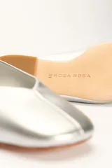 Chatas planas de cuero color plateado metálico, con punta cuadrada y un pequeño tacón bajo de madera.