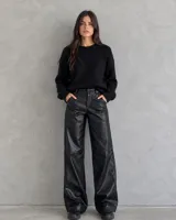 Pantalón de cuero sintético color negro, de corte ancho y holgado, con tiro medio y bolsillos laterales.